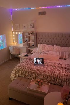 a laptop computer sitting on top of a bed next to a night stand and desk