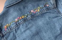 the back of a jean jacket with embroidered flowers on it