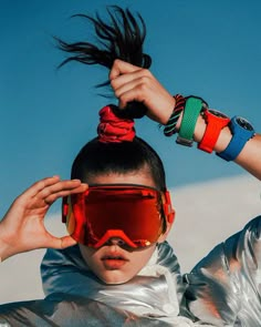 a woman wearing goggles and holding her hair in the air