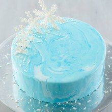 a blue frosted cake with white sprinkles on top is sitting on a glass plate