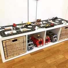 toy cars and trucks are on top of a white shelf with baskets in front of it