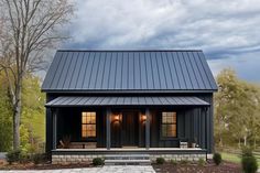 a small black house with two windows and a metal roof on the front porch area