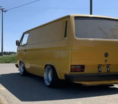 a yellow van is parked on the side of the road in front of some power lines