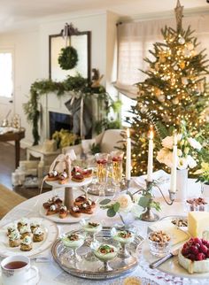 a table topped with lots of food next to a christmas tree