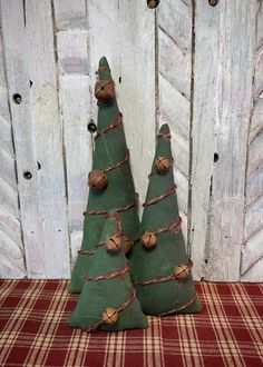 two small green christmas trees sitting on top of a red and white checkered table cloth