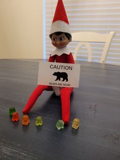 an elf sitting on top of a table holding a sign that says caution bears are near