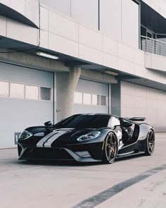 a black and white sports car parked in front of a building with two garage doors