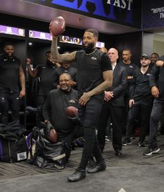 a man holding a football while standing next to another man in front of a crowd