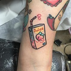 a person with a tattoo on their arm has an apple and juice drink in it