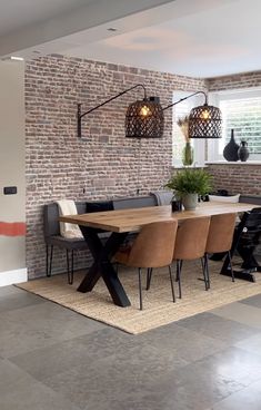 a dining room table and chairs in front of a brick wall with lights on it