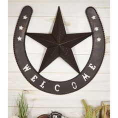 a metal star with the word welcome hanging from it's side on a wall