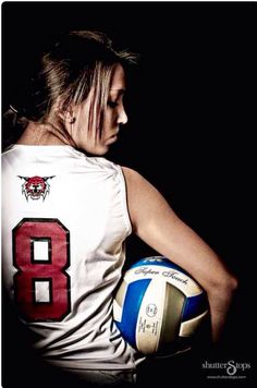 a woman holding a volleyball in her right hand and wearing a jersey with the number 8 on it