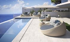 an outdoor lounge area with chairs and umbrellas next to the pool, overlooking the ocean