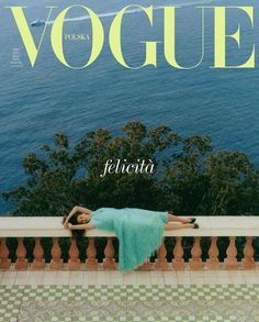 a woman laying on top of a wooden bench next to the ocean in front of a magazine cover