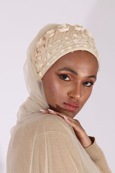 a woman wearing a white head scarf with flowers on it's side and her hand under her chin