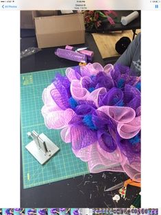 a purple and blue flower sitting on top of a table next to a pair of scissors