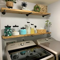 a washer and dryer in a small room with shelves above the washer