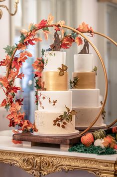 a white and gold wedding cake sitting on top of a table next to a mirror