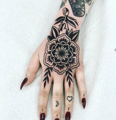 a woman's hand with black and white tattoos on her left arm, holding a flower