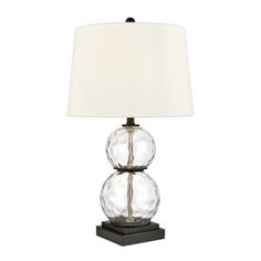 the glass table lamp has a white shade on it and is next to a black base