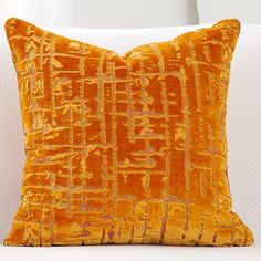 an orange pillow sitting on top of a white couch