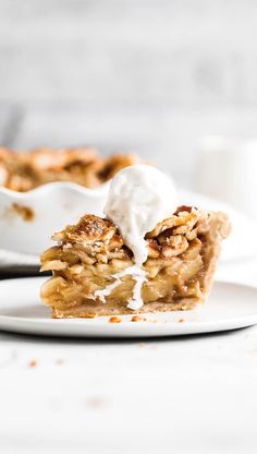 a slice of apple pie on a plate with whipped cream and fork in the background