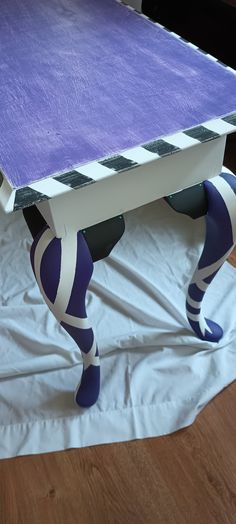 a purple and white table sitting on top of a wooden floor