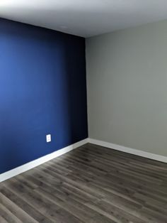 an empty room with blue walls and wood floors