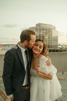 a man and woman standing next to each other in front of a cityscape