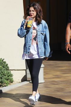 a woman walking down the street while holding a drink