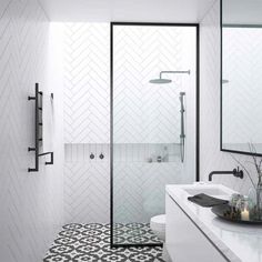 a bathroom with black and white tiles on the floor, shower stall and sink area