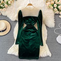 Immerse yourself in the luxury of velvet with this enchanting emerald green dress. The rich texture of the fabric is complemented by the elegant pearl beadwork that adorns the neckline, adding a touch of sophistication and vintage charm. The round neckline provides a modest canvas for the intricate pearls, making this dress a standout piece for any formal event.The dress features long sleeves and a fitted bodice that gracefully transitions into a slightly flared skirt, echoing the timeless desig Dark Green Fitted Long Sleeve Dress, Elegant Embellished Long Sleeve Dress, Green Fitted Velvet Dress With Long Sleeves, Dark Green Long Sleeve Formal Dress, Elegant Embellished Winter Dresses, Green Velvet Dress For Fall, Long Sleeve Velvet Dresses For Fall, Green Velvet Fall Dress, Elegant Green Velvet Dress For Fall