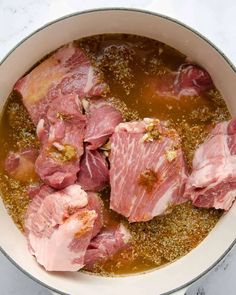 meat is being cooked in a pot with broth and seasoning on the side