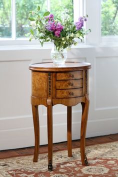 a small wooden table with flowers in a vase sitting on it's side stand