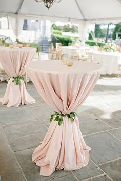 the tables are covered with pink cloths and green leaves on them for an elegant look