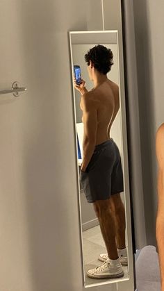 a shirtless man taking a selfie in front of a mirror with his cell phone