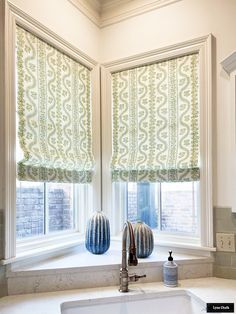 a kitchen window with two vases on the windowsill