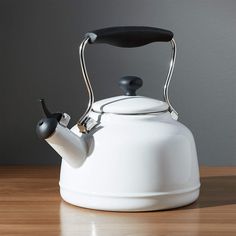 a white tea kettle with a black handle