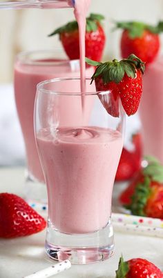 strawberry milk being poured into a glass with strawberries