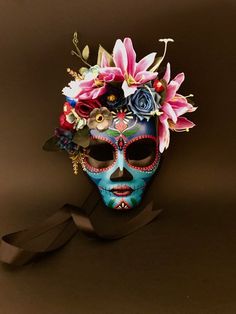 a blue skull with flowers on it's head is shown in front of a brown background