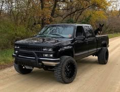 a black truck parked on top of a dirt road