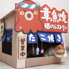 an orange and white cat sitting in a wooden toy house with chinese characters on it