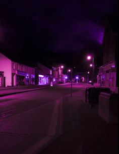 an empty city street at night with purple lights