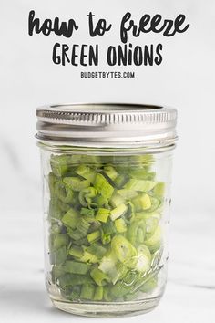 a jar filled with green onions on top of a white counter next to the words how to freeze green onions