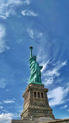 the statue of liberty in new york city is shown under a blue sky with wispy clouds