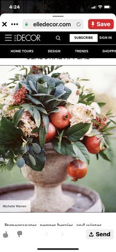 a vase filled with flowers and fruit on top of a table