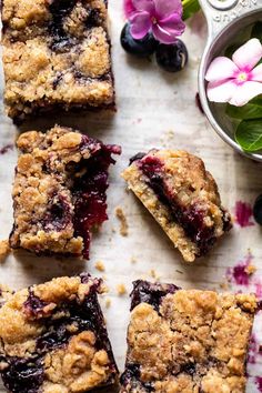 blueberry crumb bars cut into squares and placed on a table with flowers in the background