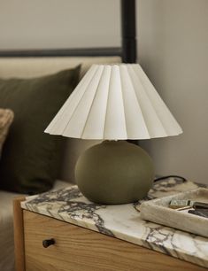 a lamp sitting on top of a table next to a bed