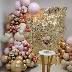 a table topped with a cake next to balloons and a wall covered in confetti