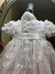 a white dress with flowers on it in front of a mirror